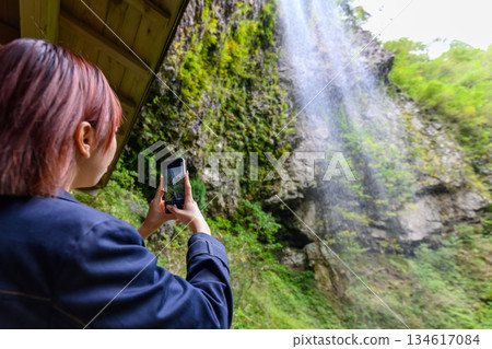 一位女士用智慧型手機拍攝瀑布照片。 134617084