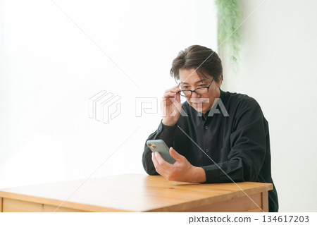 A man in his 50s operating a smartphone 134617203
