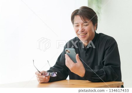 A man in his 50s operating a smartphone A man in his 50s operating a smartphone 134617433
