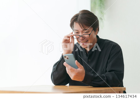 A man in his 50s operating a smartphone A man in his 50s operating a smartphone 134617434