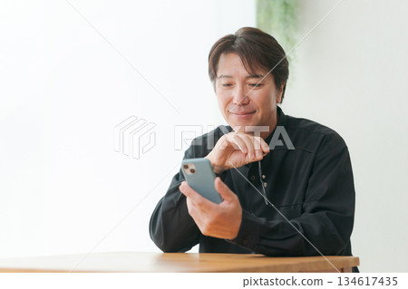 一名五十多歲的男子正在操作智慧型手機 134617435