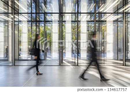 Professional individuals in dark suits walking through a modern business setting 134617757