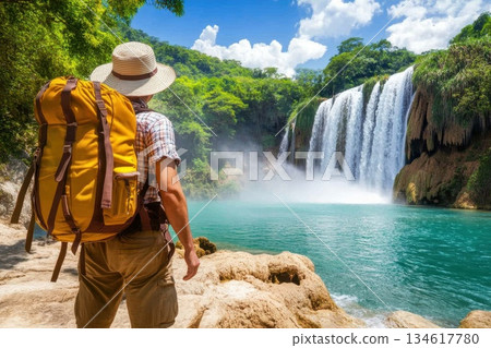 Adventurous Explorer Enjoying Scenic Waterfall Landscape in Lush Green Nature 134617780
