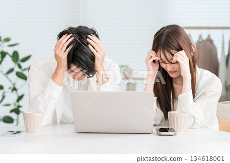 A young couple is shocked while looking at a computer in their living room at home A young couple is shocked while looking at a computer in their living room at home 134618001