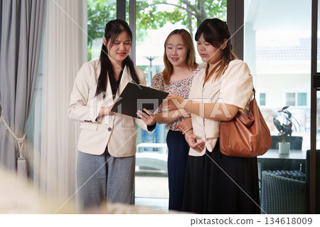 Real Estate. Clients reviewing property details with realtor, discussing home features. 134618009