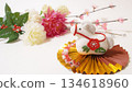 A crepe white horse figurine on a golden fan and New Year's flowers 134618960