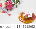 A crepe white horse figurine on a gold fan and New Year's flowers 134618962
