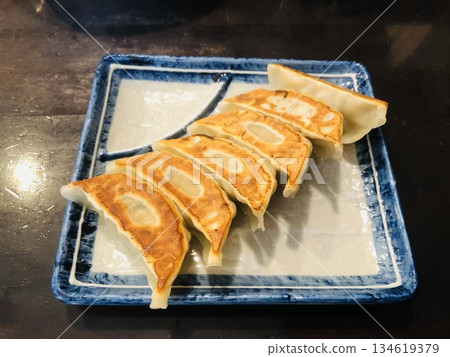 Six fried gyoza dumplings on a square plate 134619379