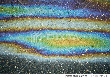 Colorful Patterns on Wet Asphalt After Rain Show Various Shades in a City Street During Daytime in an Urban Area. Colorful Patterns on Wet Asphalt After Rain Show Various Shades in a City Street During Daytime in an Urban Area. 134619421
