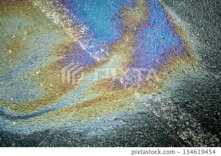 Gasoline slick creating an iridescent rainbow pattern on dark wet pavement Gasoline slick creating an iridescent rainbow pattern on dark wet pavement 134619454
