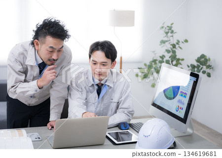 Two businessmen in work clothes talking while looking at a computer. Image of DX and IT in the manufacturing industry 134619681