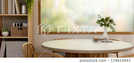 Coffee cup with books on a round wooden table next to the large window with scenery outside the cafe 134619941