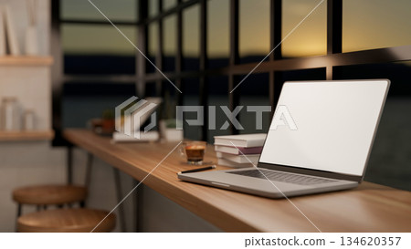 White screen laptop and coffee in glass cup with books on wooden table in cafe with evening sunset. 134620357