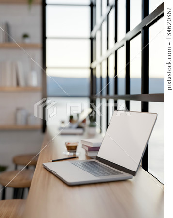 Blank screen laptop and coffee in glass cup with books on wooden table with chairs in a seaside cafe 134620362