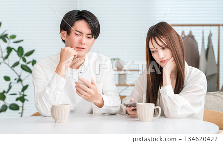 Couple having a conversation while drinking hot drinks at the dining table Couple having a conversation while drinking hot drinks at the dining table 134620422