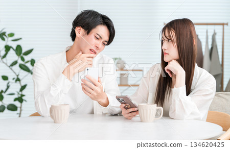 Couple having a conversation while drinking hot drinks at the dining table Couple having a conversation while drinking hot drinks at the dining table 134620425