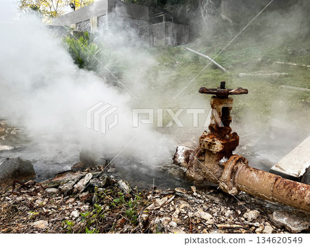 Rusty geothermal pipe releasing hot steam at a natural hot spring, representing geothermal energy, underground heat, pressure system, renewable power generation from Earth natural resources, Broken 134620549