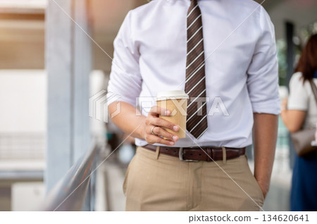 Close up businessman office worker holding coffee hand in pocket standing on pedestrian footbridge Close up businessman office worker holding coffee hand in pocket standing on pedestrian footbridge 134620641