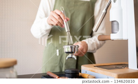 Close up of barista using brush cleaning used coffee ground in machine container at cafe counter bar Close up of barista using brush cleaning used coffee ground in machine container at cafe counter bar 134620810