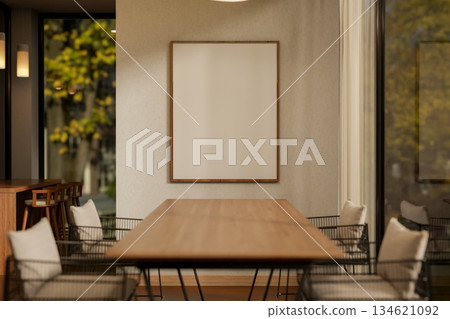 Wooden table and steel chair in dining room of a cafe or restaurant with blank white frame on wall. 134621092