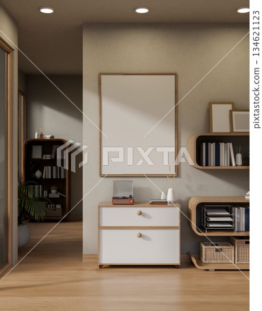 A vinyl player on wooden drawer cabinet under blank frame on wall next to a stylish bookshelf in a modern living room. 134621123