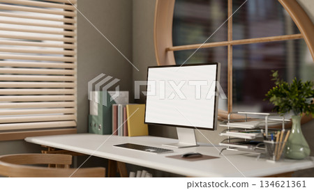 Blank screen computer with books and folders on wooden table under window in bedroom or living room. 134621361