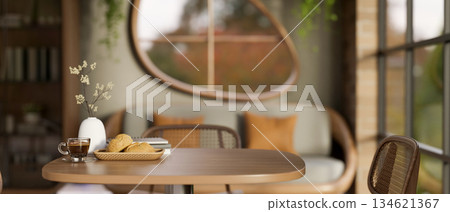 Breads on plate with a cup of coffee aside books and vase on wooden stool table in a lounge or cafe. Breads on plate with a cup of coffee aside books and vase on wooden stool table in a lounge or cafe. 134621367