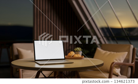 Coffee cup aside book on a round wooden table with armchair in living room or cafe under roof window Coffee cup aside book on a round wooden table with armchair in living room or cafe under roof window 134621373