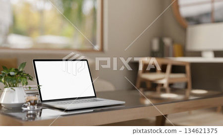 White screen laptop with books and coffee cup on glass top wooden table in a bedroom or living room. 134621375