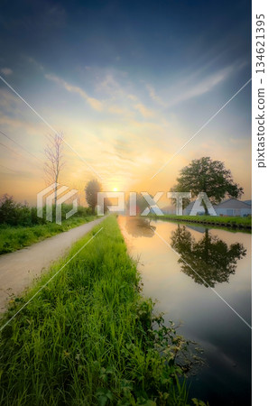 A Serene Sunset Over the Picturesque Canal with Beautiful Reflections and Lush Greenery A Serene Sunset Over the Picturesque Canal with Beautiful Reflections and Lush Greenery 134621395