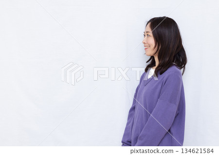 A woman wearing a purple knit sweater looking sideways 134621584
