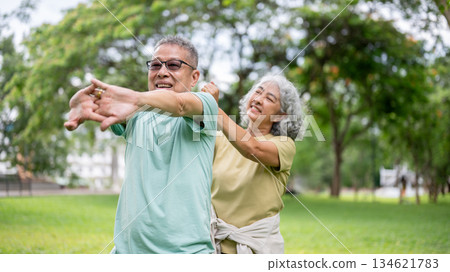 Old woman massaging glasses man shoulders while he standing and stretching on grass lawn in the park Old woman massaging glasses man shoulders while he standing and stretching on grass lawn in the park 134621783