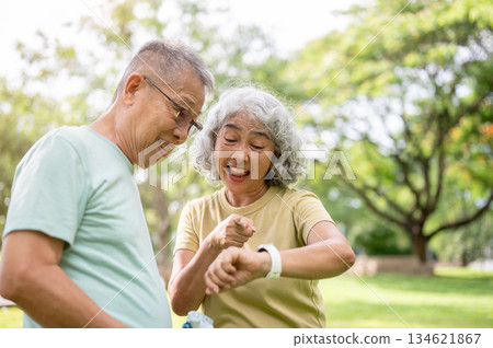 Old woman looking and pointing at wristwatch to old man after finish exercise in time at the park. Old woman looking and pointing at wristwatch to old man after finish exercise in time at the park. 134621867