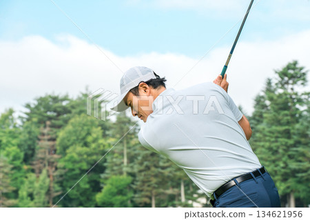 A golfer man hitting a tee shot on a golf course (golf swing) 134621956