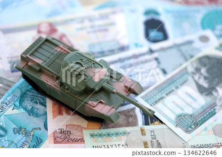Egyptian pound currency money bills and toy tank close up. The concept of army funds and weapons sales Egyptian pound currency money bills and toy tank close up. The concept of army funds and weapons sales 134622646