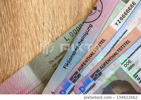 German Permanent resident card and document specimen lies on wooden table close up. Aufenthaltstitel and Fiktionsbescheinigung German Permanent resident card and document specimen lies on wooden table close up. Aufenthaltstitel and Fiktionsbescheinigung 134622662