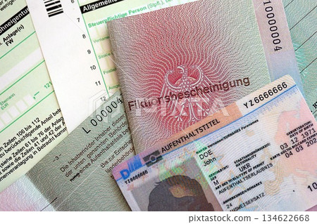 German Permanent resident card and temporary document lies on tax form close up. Aufenthaltstitel and Fiktionsbescheinigung 134622668