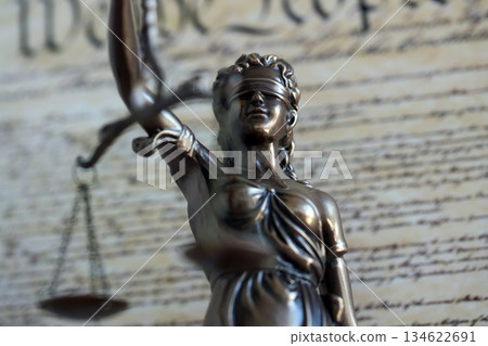 Lady Justice statue with scales on background of US Constitution page close up. Lawsuit and punishment in United States 134622691