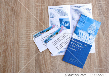 Permanent resident green card in envelope and guide for new immigrants lies on wooden table close up 134622718