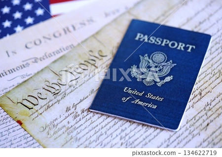 US passport on replica pages of the United States Constitution close up with US flag background 134622719