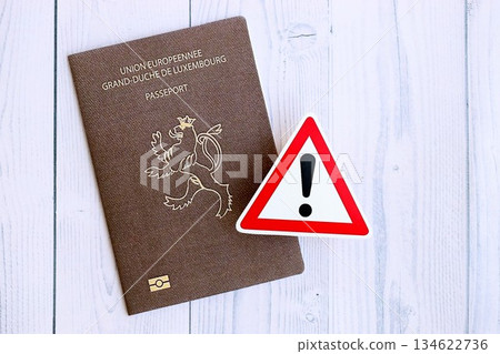 Luxembourg passport with exclamation sign on white wooden background close up. Problems with citizenship in Europe concept Luxembourg passport with exclamation sign on white wooden background close up. Problems with citizenship in Europe concept 134622736