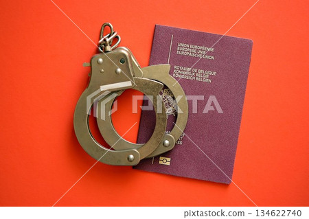 Belgium passport with police handcuffs on table close up. Criminal level and arrests in Europe concept Belgium passport with police handcuffs on table close up. Criminal level and arrests in Europe concept 134622740