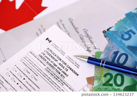 Canadian certificate of citizenship and application with money on Canadian flag close up Canadian certificate of citizenship and application with money on Canadian flag close up 134623237