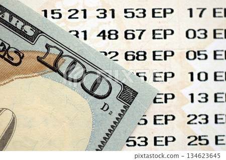 Lottery ticket and one hundred US dollar bill close up. Concept of gambling addiction and lottery Lottery ticket and one hundred US dollar bill close up. Concept of gambling addiction and lottery 134623645