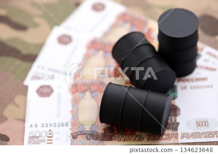 Three oil barrels on russian roubles money bills on camouflage fabric. Concept of oil export from Russia Three oil barrels on russian roubles money bills on camouflage fabric. Concept of oil export from Russia 134623648
