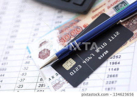 Credit card and pen with russian ruble currency money bills banknotes on calculations document background. Business, financial operations and accounting in Russian Federation Credit card and pen with russian ruble currency money bills banknotes on calculations document background. Business, financial operations and accounting in Russian Federation 134623656