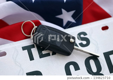 Remote control car keys on Texas license plate on US flag. Concept of driving in Texas. Reaching a driving permit Remote control car keys on Texas license plate on US flag. Concept of driving in Texas. Reaching a driving permit 134623710
