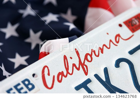 USA state of California license plate on US flag. Concept of driving in California. Reaching a driving permit USA state of California license plate on US flag. Concept of driving in California. Reaching a driving permit 134623768