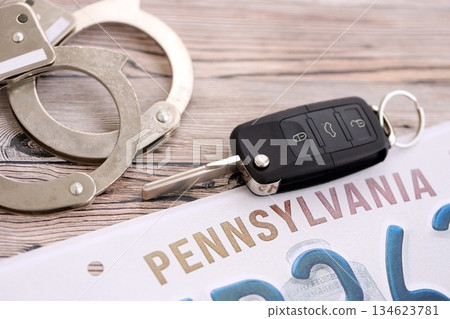 Remote control car keys on Pennsylvania license plate and handcuffs. Concept of car accident in Pennsylvania. Breaking the law 134623781