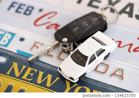 Remote control car keys on US license plates with state names close up. Concept of driving in United States. Reaching a car registration 134623785